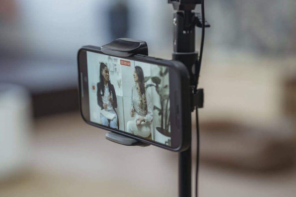 Modern smartphone on tripod recording video of content stylish women having friendly conversation